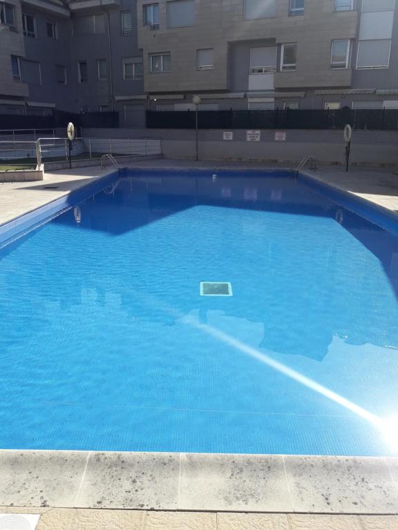 a large blue swimming pool in front of a building at Duplex con piscina VUT1230AS in San Juan de la Arena