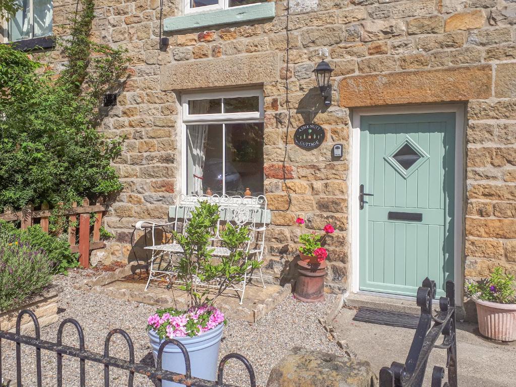 a stone house with a green door and a window at Ashknott Cottage in Ripon