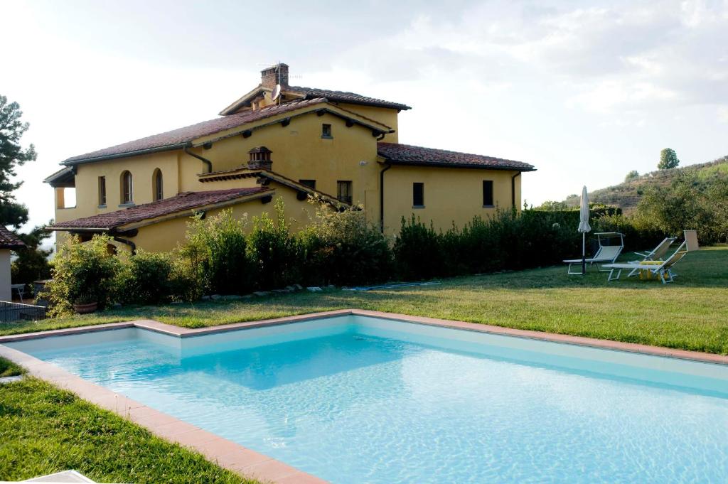 une grande piscine en face d'une maison dans l'établissement Il Bellini, à Castelfranco di Sopra