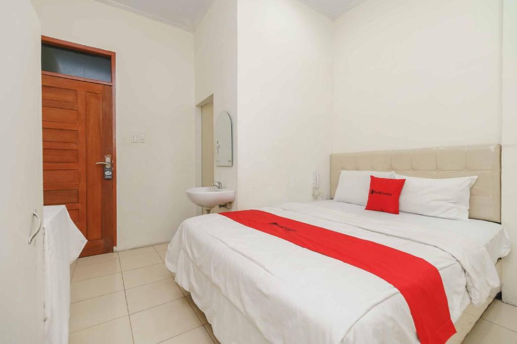a bedroom with a large white bed with a red pillow at RedDoorz @ Haraito Tarutung in Tarutung