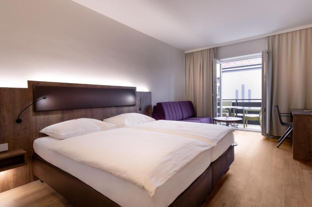 una camera con un grande letto e un balcone di City Hotel Stockerau a Stockerau