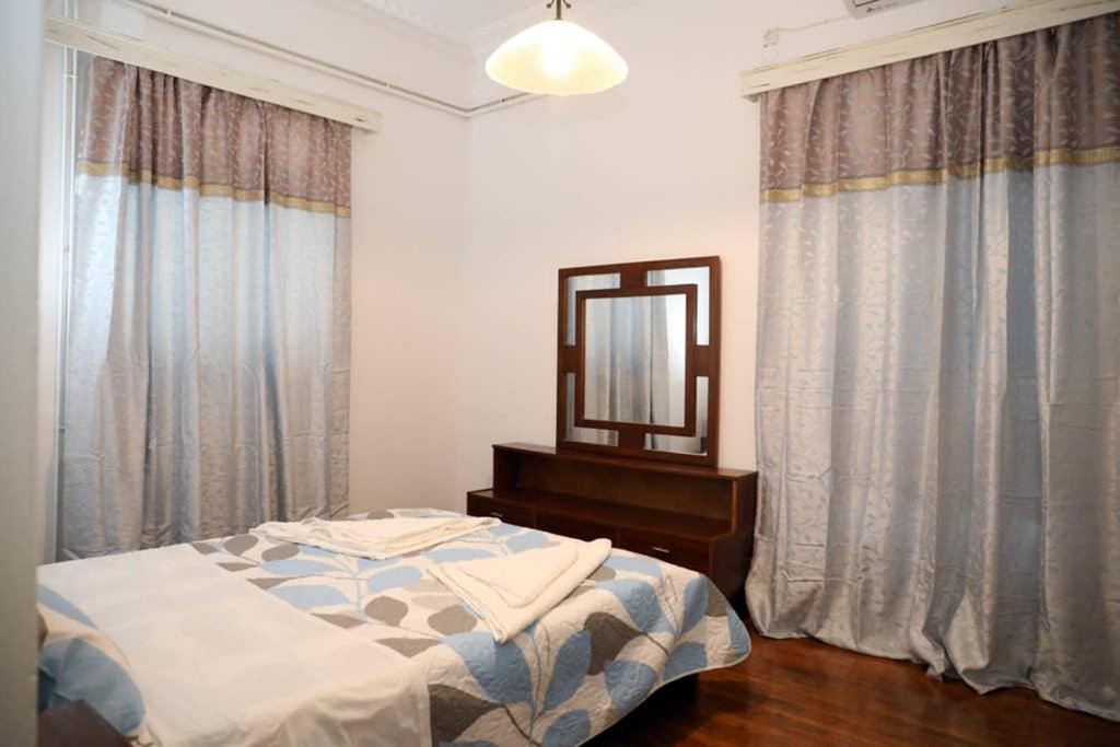 a bedroom with a bed and a mirror and curtains at Andreas Naxos Center - House in Naxos Chora