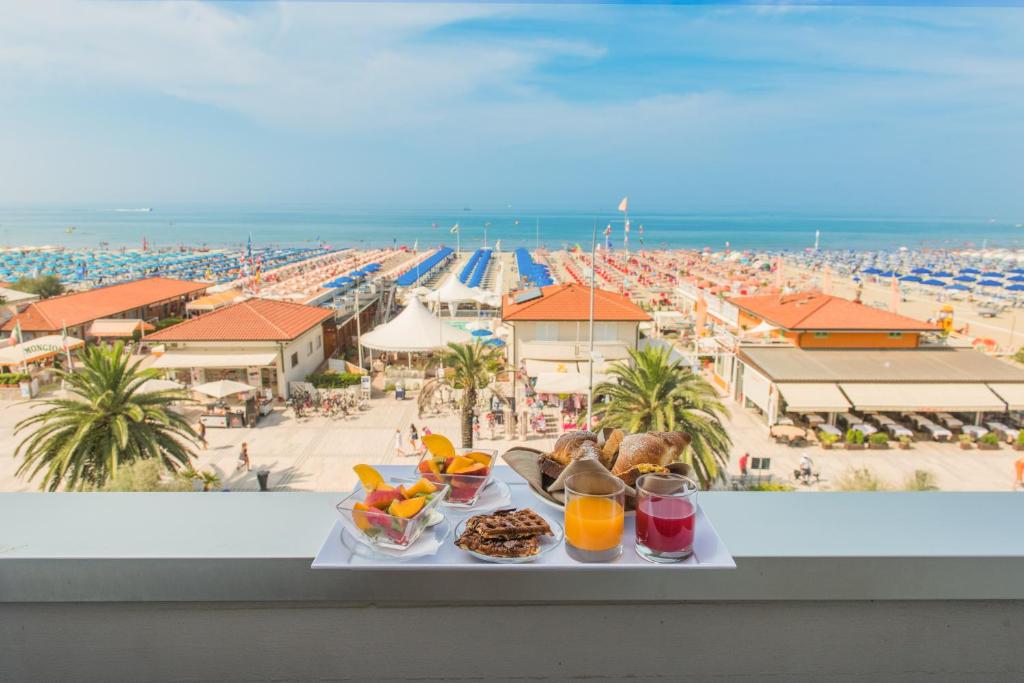 a tray of food on a ledge with a view of a beach at Hotel Giulia in Lido di Camaiore