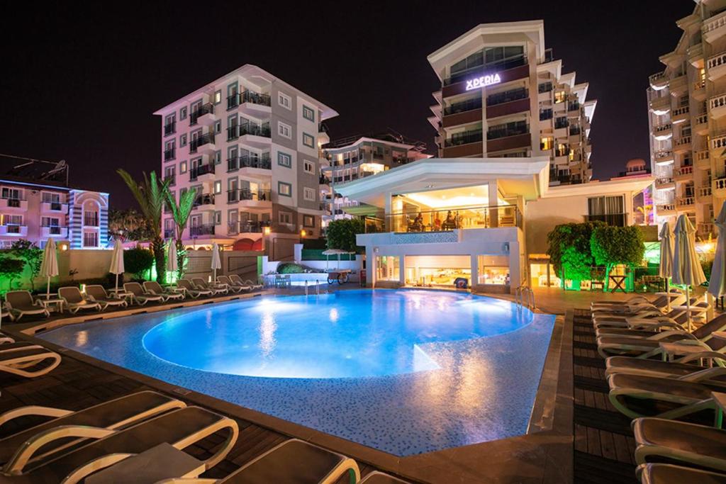 a large swimming pool with chairs and buildings at night at Xperia Saray Beach Hotel in Alanya