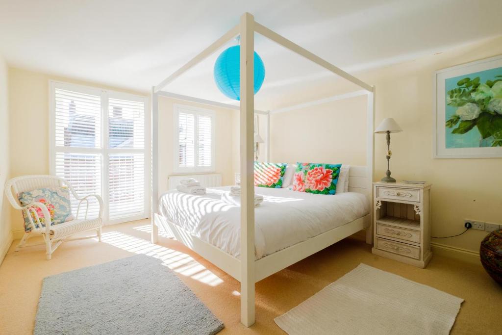 ein Schlafzimmer mit einem weißen Himmelbett und einem Stuhl in der Unterkunft Shell Cottage in Aldeburgh