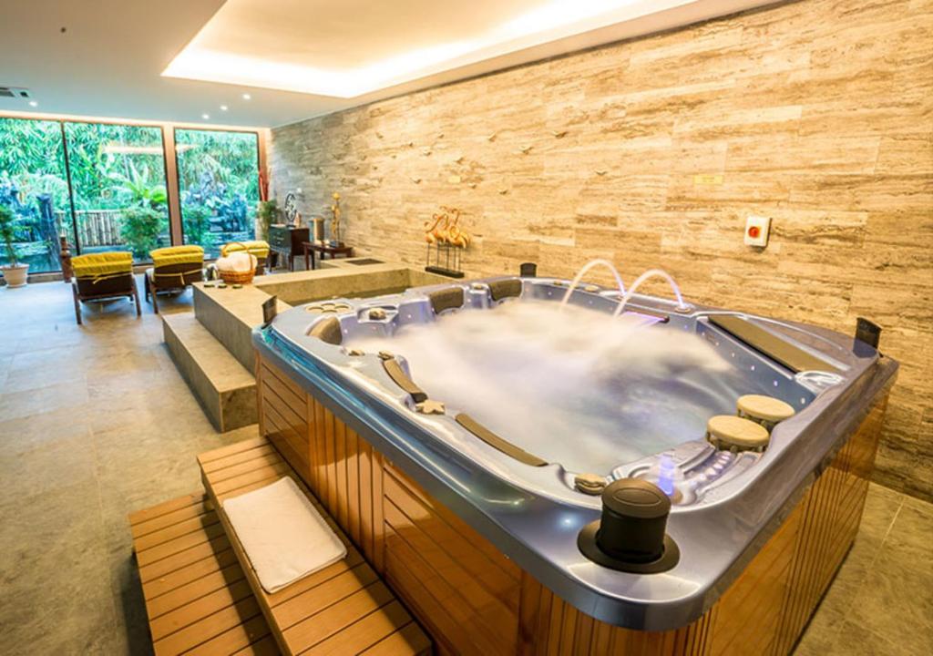 a large bath tub in a room with a stone wall at The Orchard Resort & Spa Melaka I World Spa Awards Winner I Free Access to Outdoor Spa Pool in Melaka