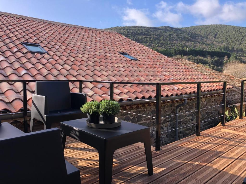 uma varanda com uma mesa e cadeiras e um telhado em La Maison Cayre, stylish house and terrace, Berlou, natural park em Berlou
