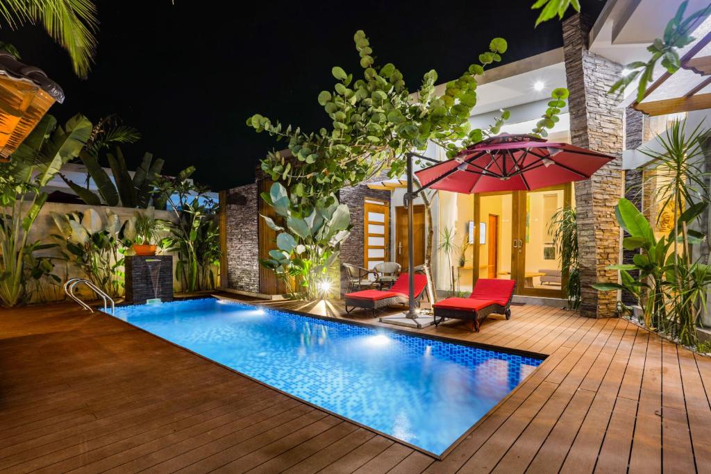 a swimming pool in a backyard with a red umbrella at Maneh Villa Langkawi - Private Pool in Pantai Cenang