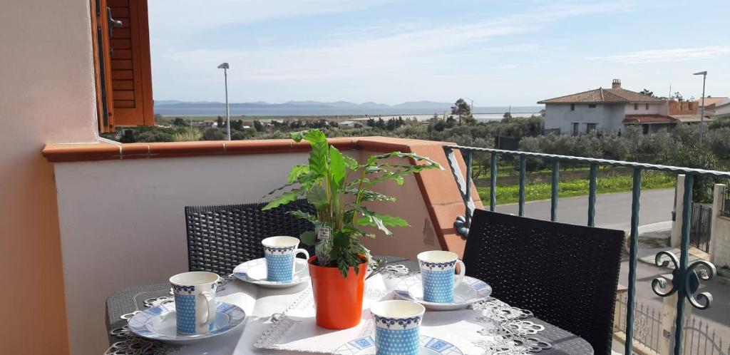 une table avec des assiettes et des tasses et une plante sur un balcon dans l'établissement Villa Rosa, à SantʼAntìoco
