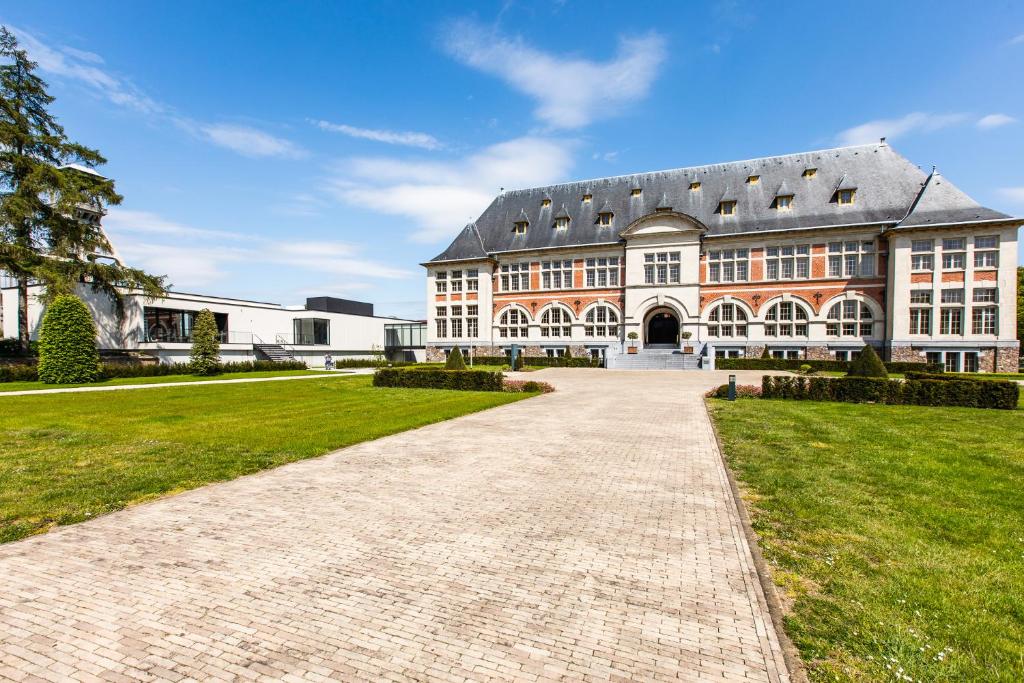 an exterior view of a large building with a driveway at Terhills Hotel in Maasmechelen