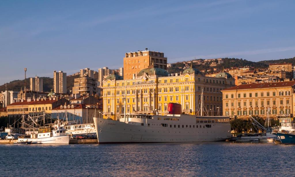 ein Kreuzfahrtschiff, das in einem Hafen mit Gebäuden angedockt ist in der Unterkunft Botel Marina in Rijeka