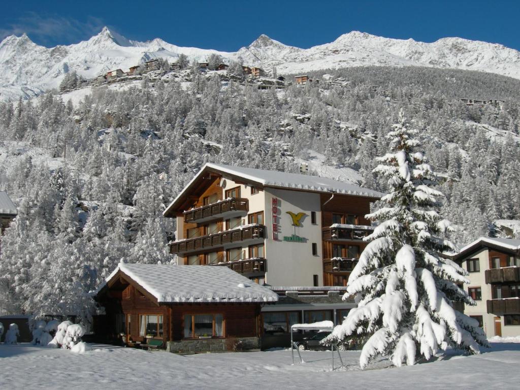 a hotel in the snow with a snow covered mountain at Hotel Adler in Saas-Grund