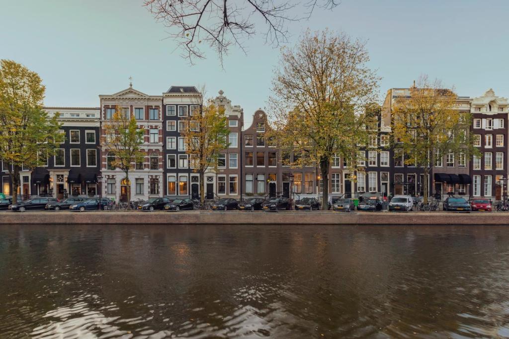eine Reihe von Gebäuden neben einem Fluss mit Autos in der Unterkunft The Pavilions Amsterdam, The Toren in Amsterdam