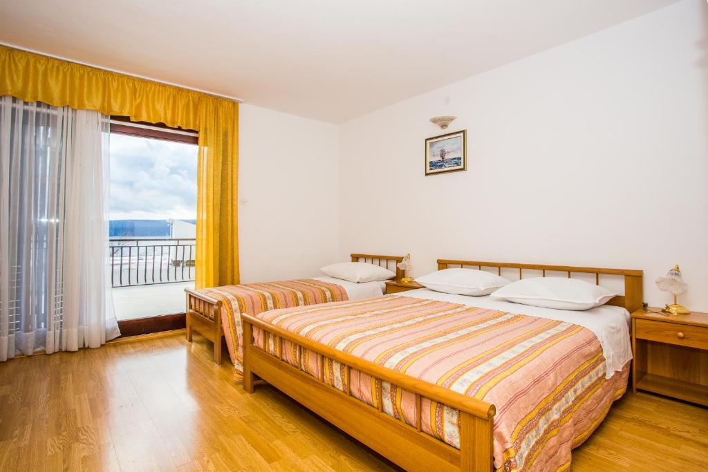 a bedroom with two beds and a large window at Apartmani Pava in Omiš