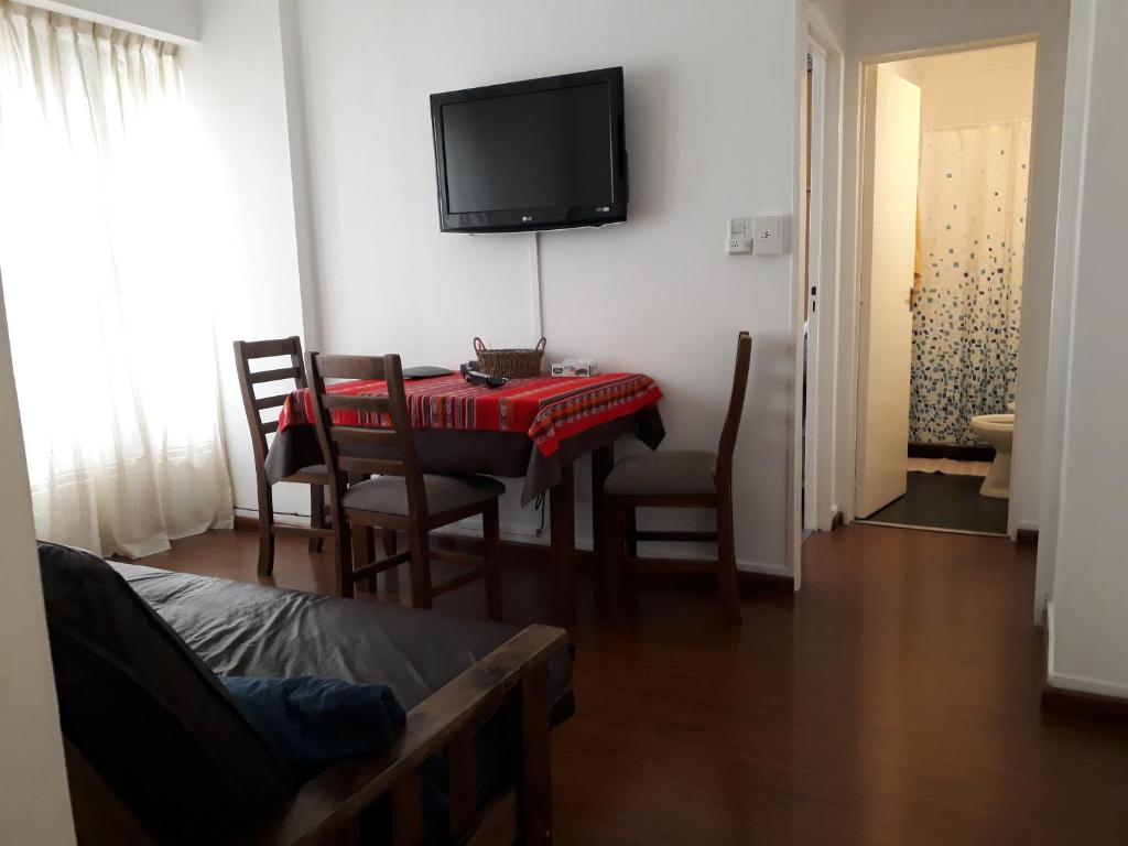 ein Wohnzimmer mit einem Tisch und einem TV an der Wand in der Unterkunft Apartamento Avenida de Mayo 1316 in Buenos Aires