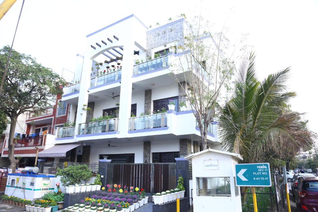biały budynek z balkonem przy ulicy w obiekcie joerose villa w mieście Noida