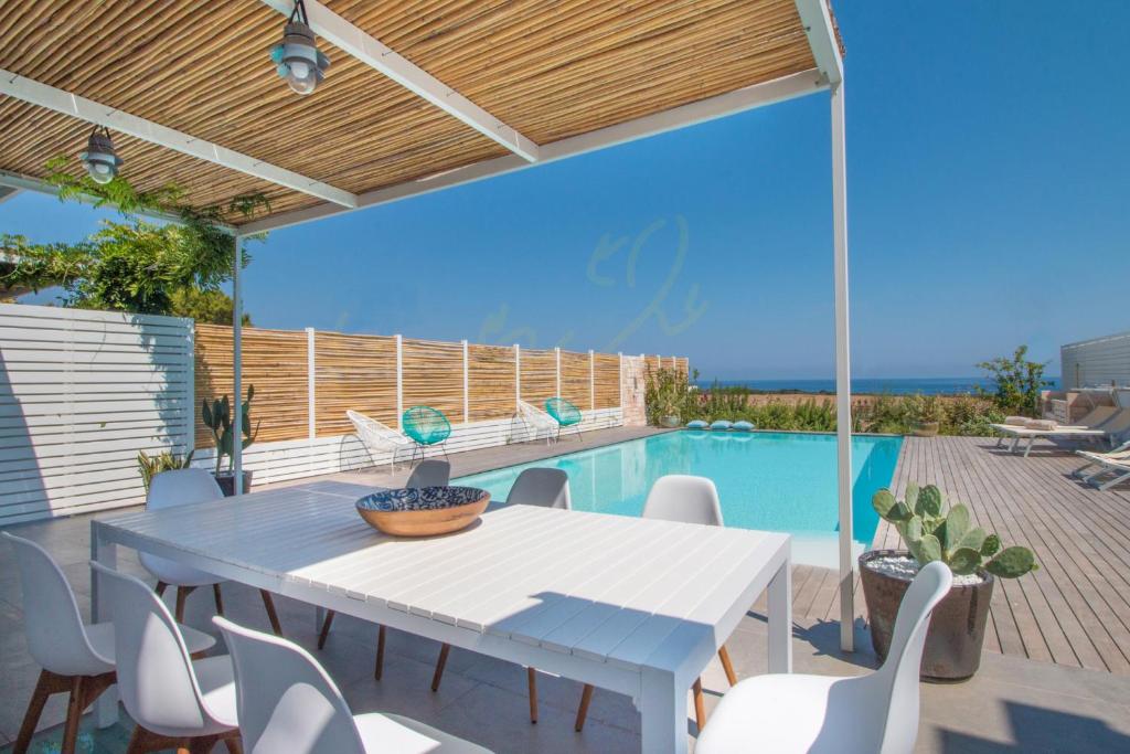 un patio avec une table et des chaises et une piscine dans l'établissement TD Villa Levante Modern Luxury Villa with Sea View, à Monopoli