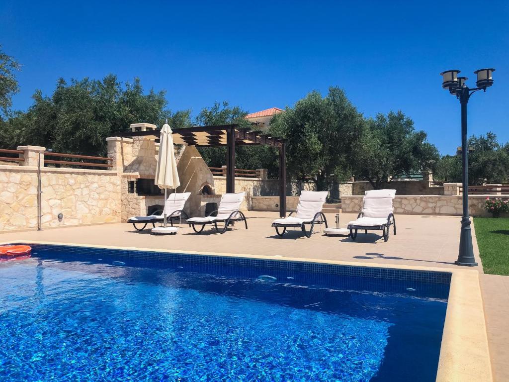 a group of chairs and a swimming pool at Levanda Luxury Stone Villa in Kalyves