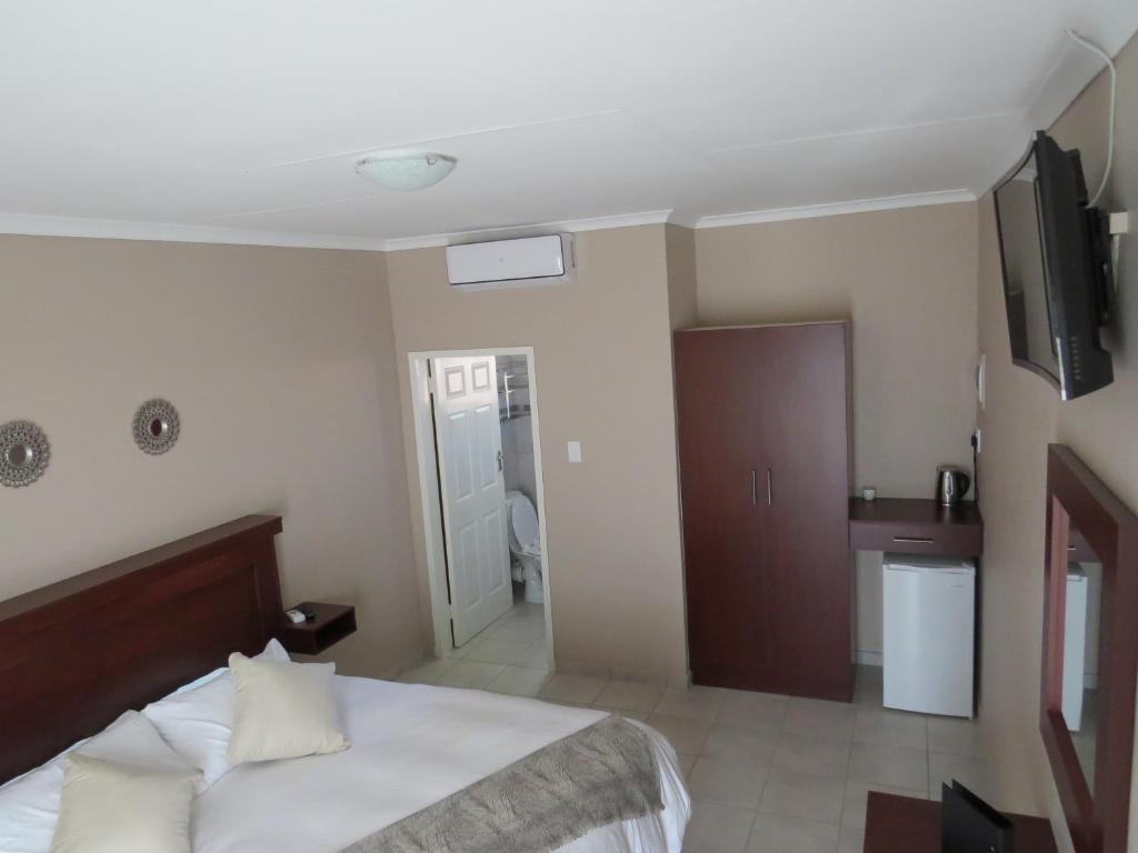 a bedroom with a bed and a tv on the wall at Villa Strada Guesthouse in Klerksdorp