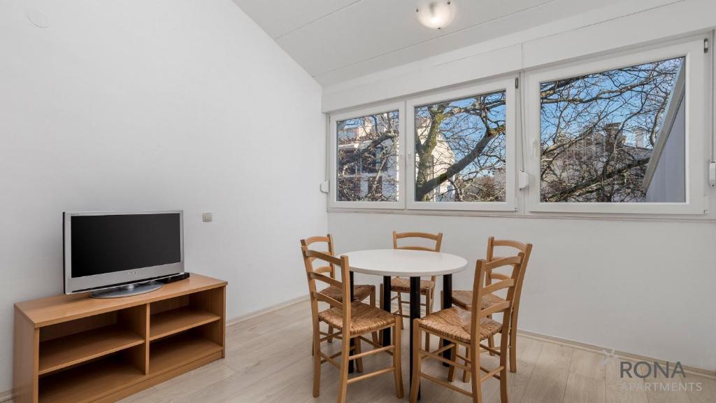 ein Esszimmer mit einem Tisch und Stühlen sowie einem TV in der Unterkunft Rona Apartments Volta in Poreč