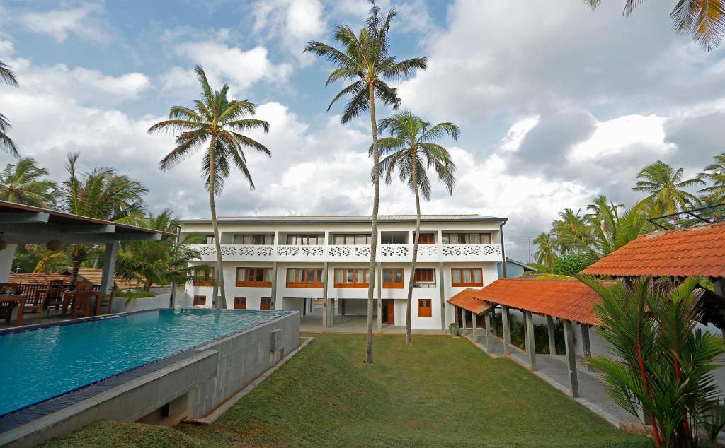 a building with a swimming pool and palm trees at The Beach Boutique in Uswetakeiyawa