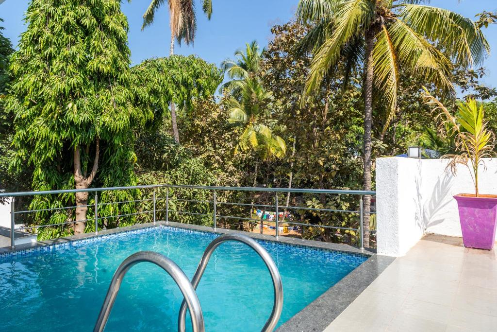 a swimming pool with a fence and palm trees at Amara Baga Villa 5BHK in Baga