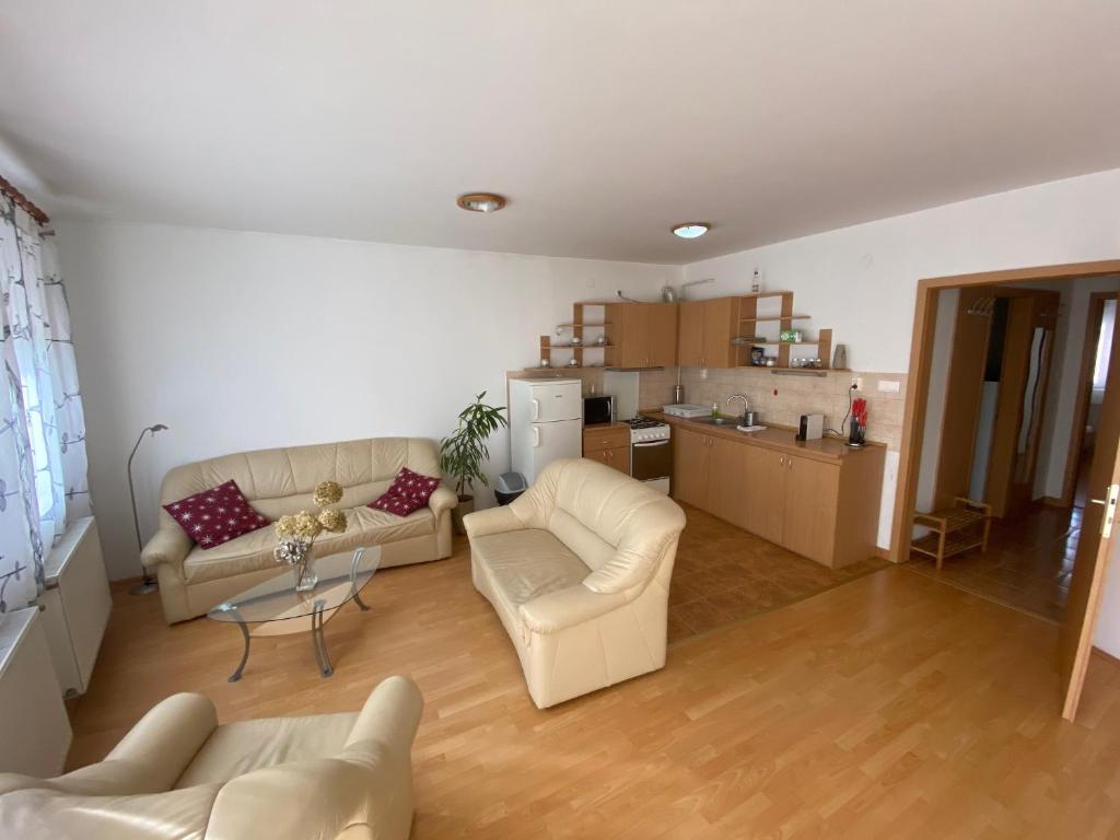 a living room with two white couches and a kitchen at iHome Apartment 3.0 in Pécs