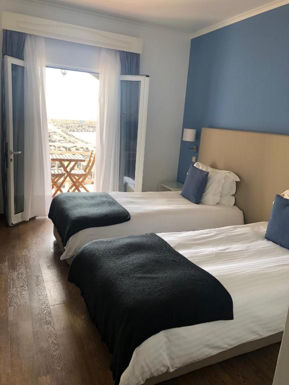 two beds in a hotel room with a window at Vinha da Areia Beach Hotel in Vila Franca do Campo