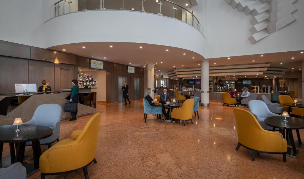 a lobby with people sitting at tables and chairs at Maldron Hotel Belfast International Airport in Aldergrove