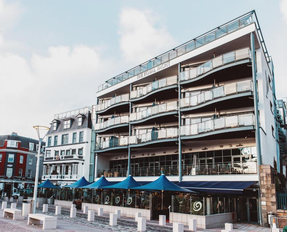 un edificio con sombrillas azules delante de él en The Royal Yacht, en Saint Helier Jersey