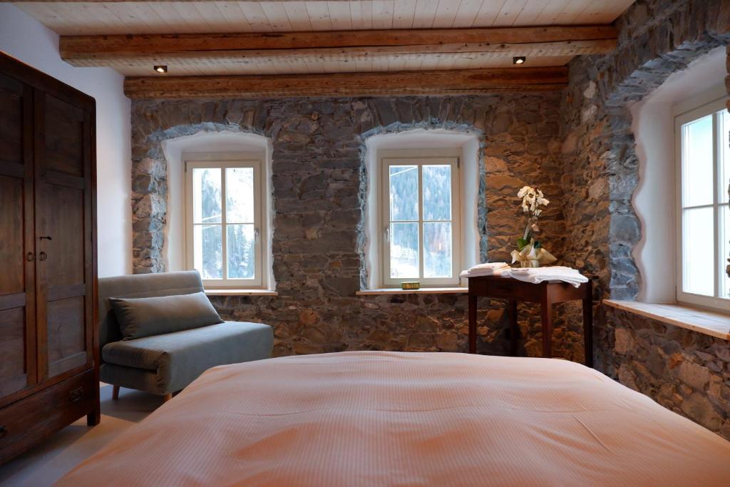 a bedroom with a bed and a chair and windows at Appartamenti La Rocia in Rocca Pietore