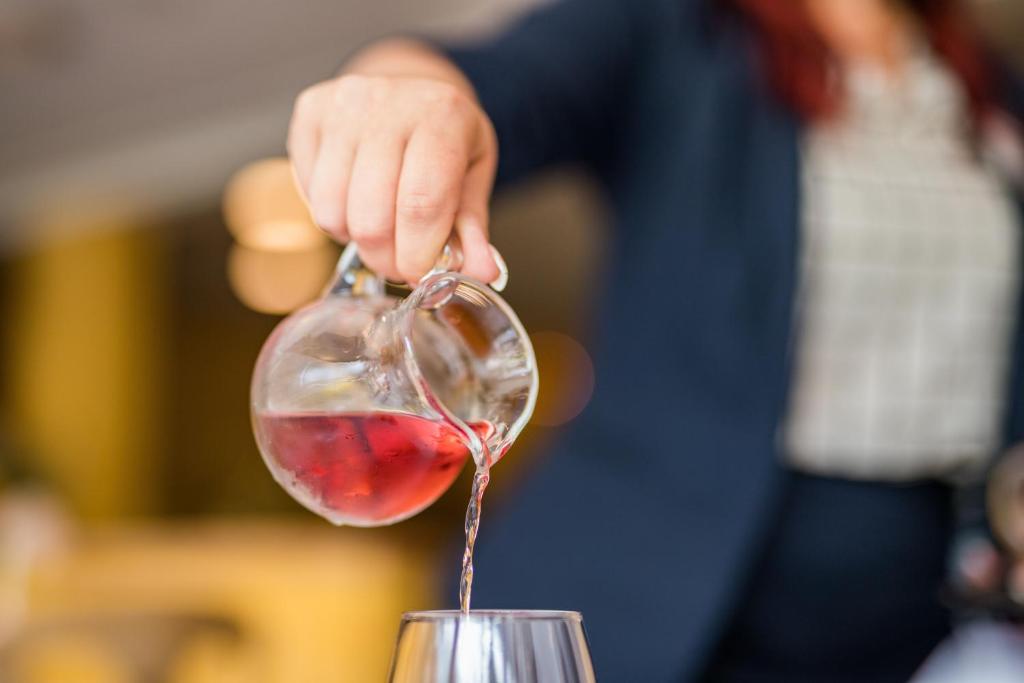 a person is pouring wine into a wine glass at Hotel am Schloß Apolda in Apolda