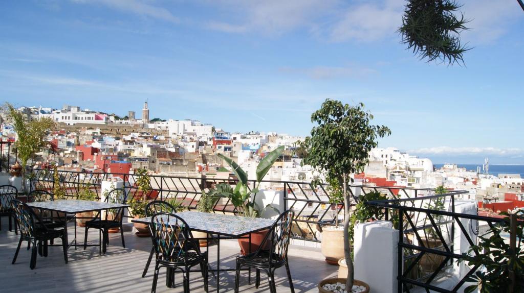 uma varanda com mesas e cadeiras e vista para a cidade em Riad Tingis em Tânger