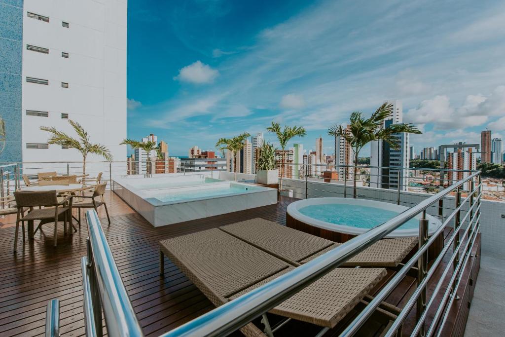 uma varanda com uma piscina, uma mesa e cadeiras em Guest Manaíra Apart Hotel em João Pessoa