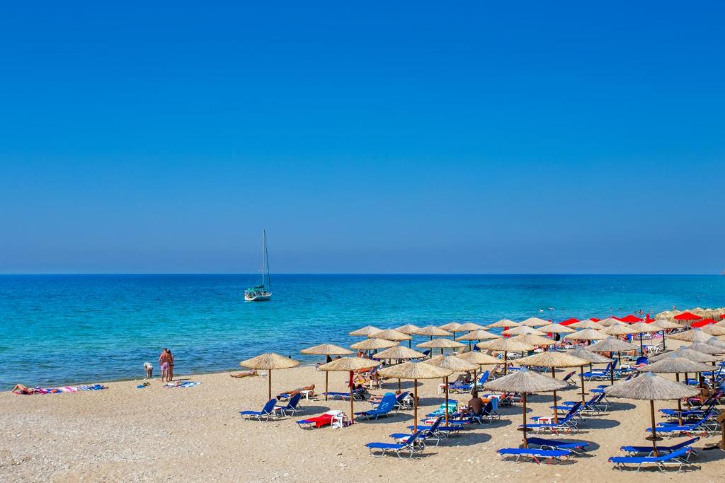 una spiaggia con molte sedie e ombrelloni e l'oceano di Apartments Ralitsa a Limenaria