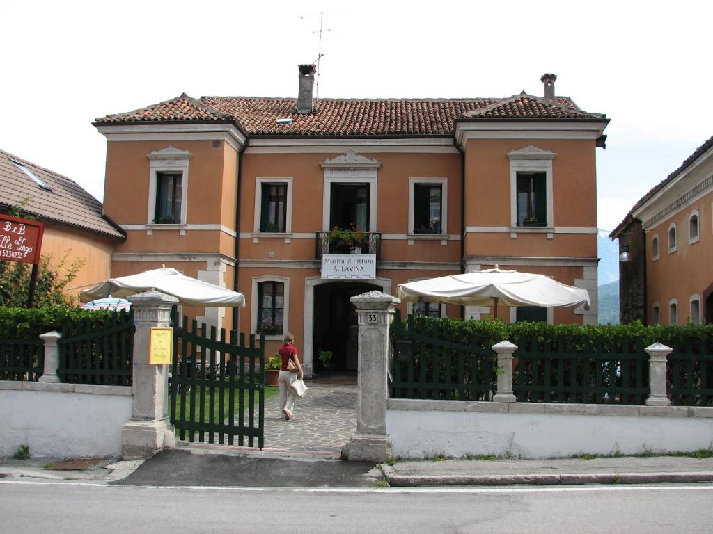 a person walking past a fence in front of a building at B&B Villa al Lago in Farra dʼAlpago