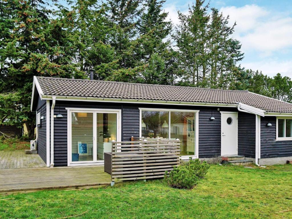een klein huis met een houten terras in een tuin bij 5 person holiday home in TRELLEBORG in Trelleborg