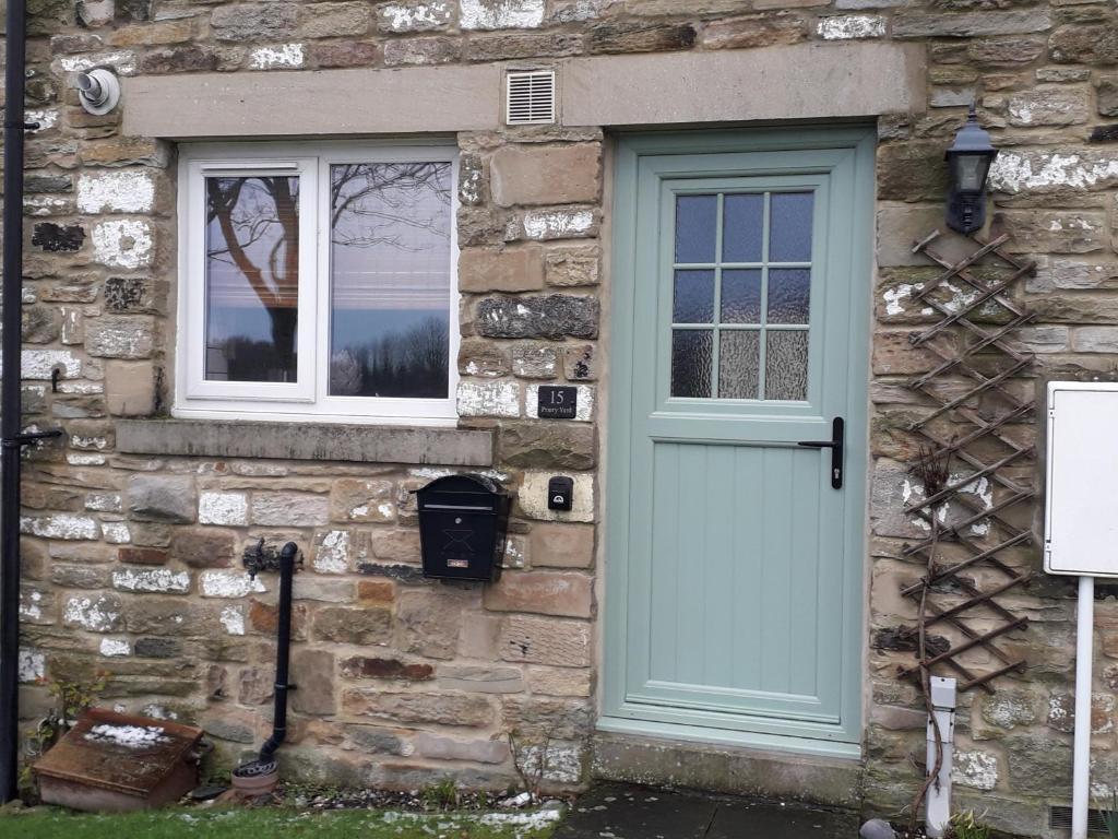 a stone house with a blue door and two windows at Demesnes View in Barnard Castle