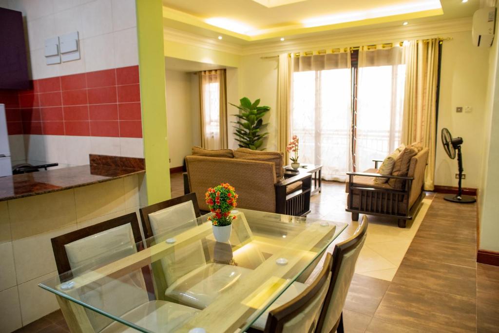 a kitchen and living room with a table and chairs at Dina Apartments in Kampala