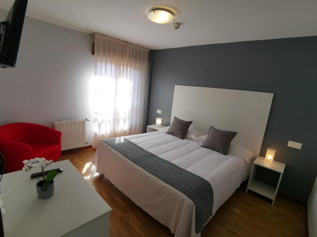 a bedroom with a large bed and a red chair at Hotel El Trasgu in Cangas de Onís