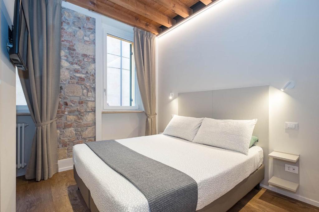 ein Schlafzimmer mit einem Bett und einer Ziegelwand in der Unterkunft Teatro Romano Easy Suites in Verona