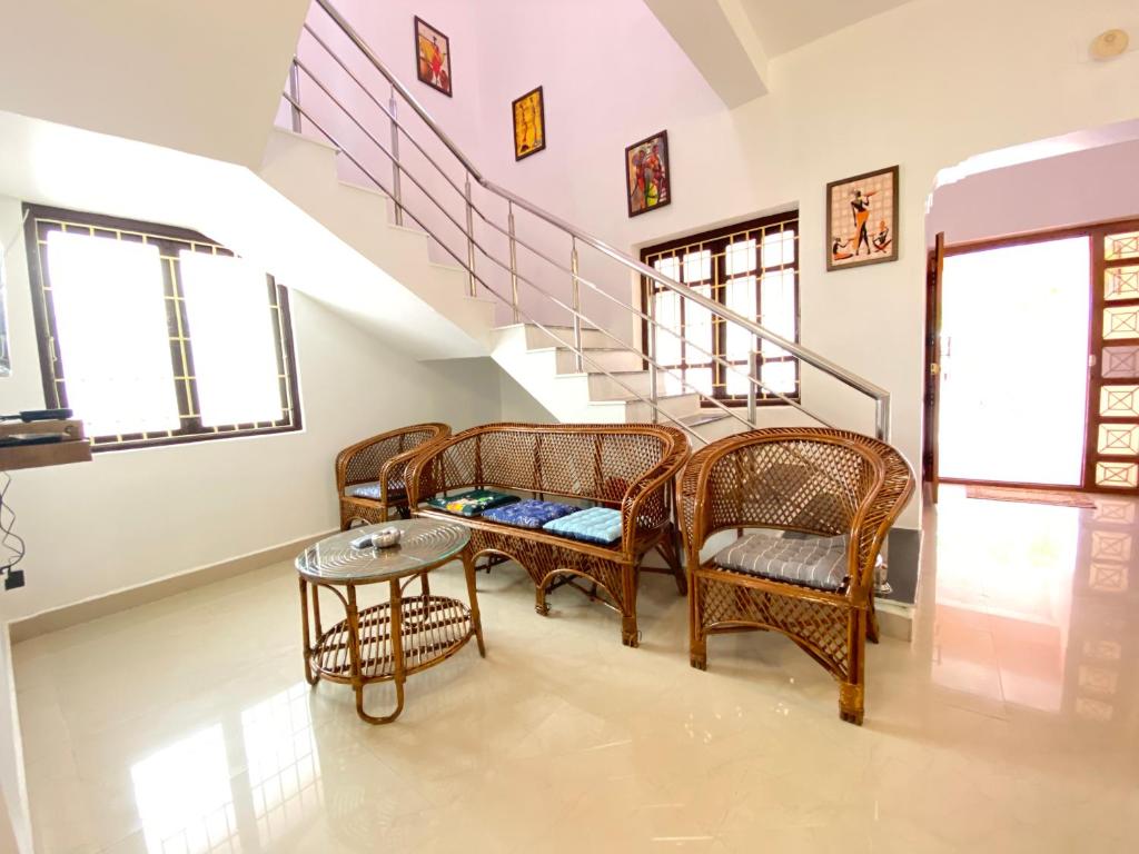 sala de estar con sillas de mimbre y escalera en Le Royce Townhouse Villa - TIE, en Pondicherry