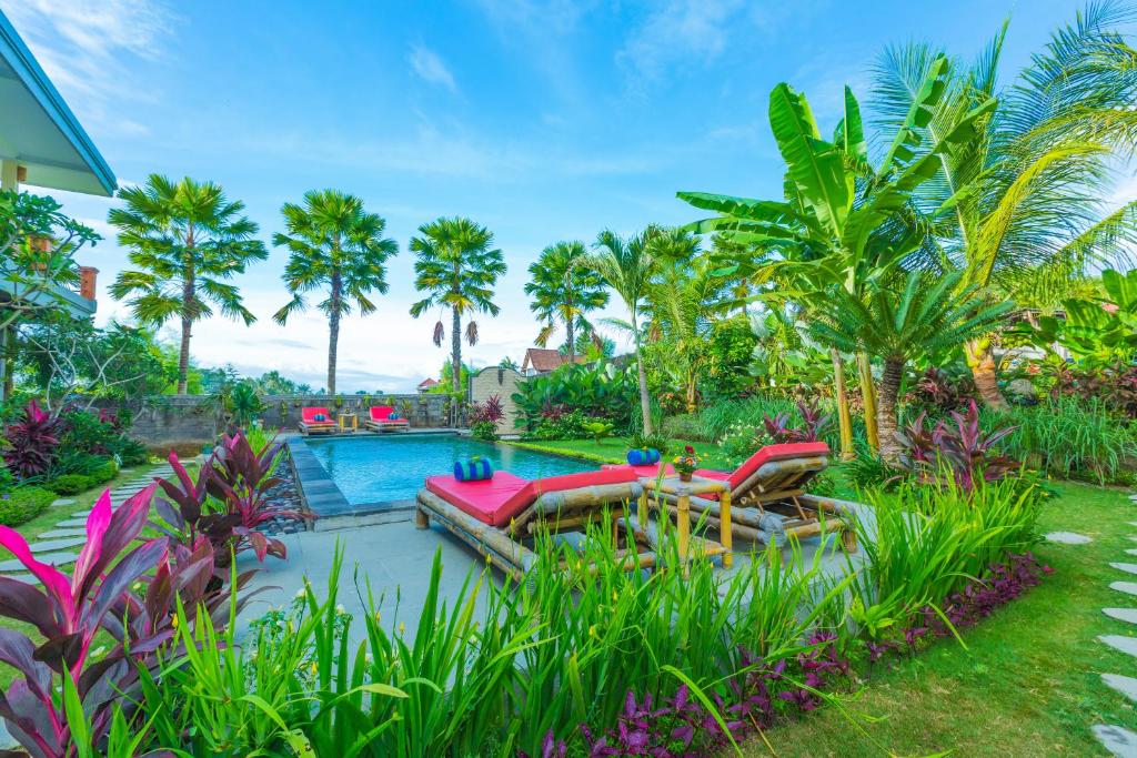 un cortile con piscina, sedie e palme di Tantra House Ubud ad Ubud
