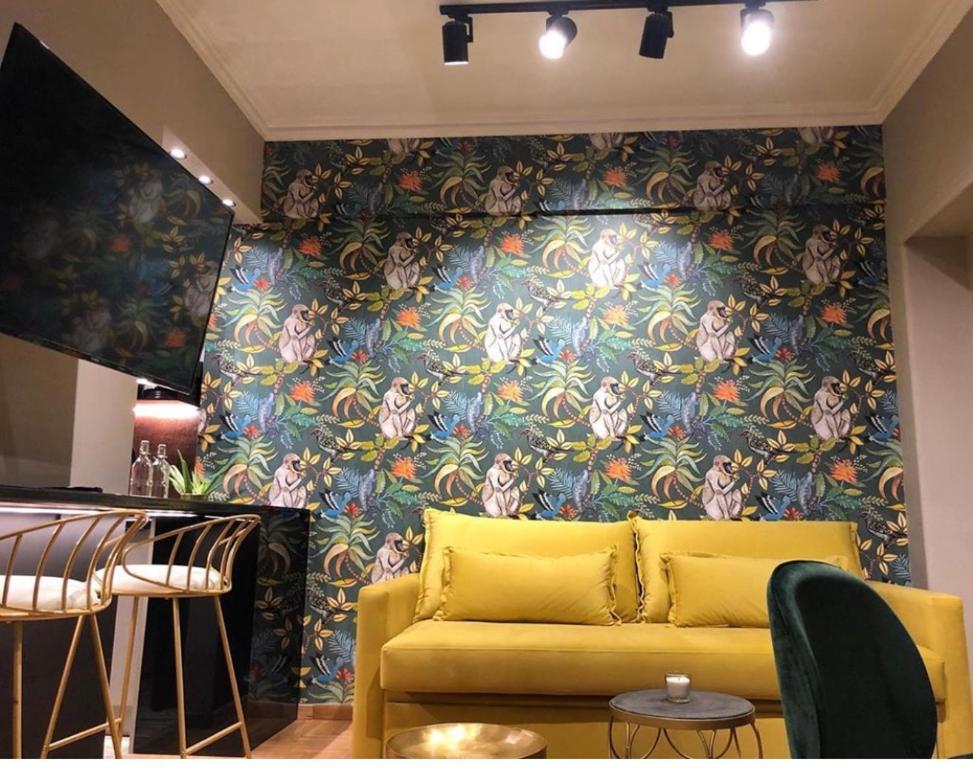 a yellow couch in a room with a floral wall at Soho Apartments in Athens