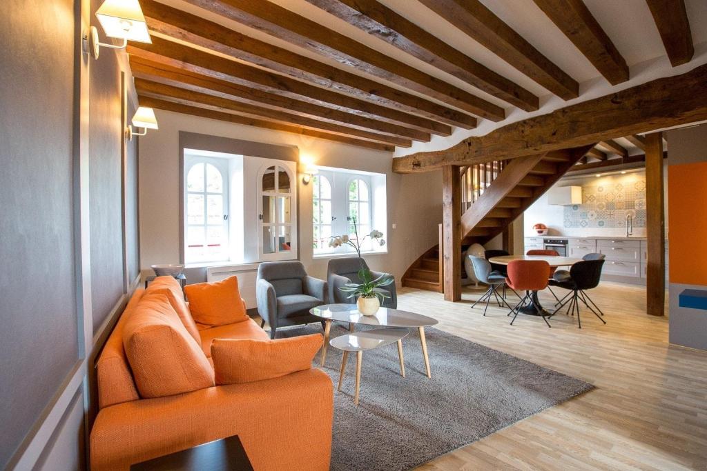 a living room with an orange couch and a table at Les Suites du Château de Cheverny in Cheverny