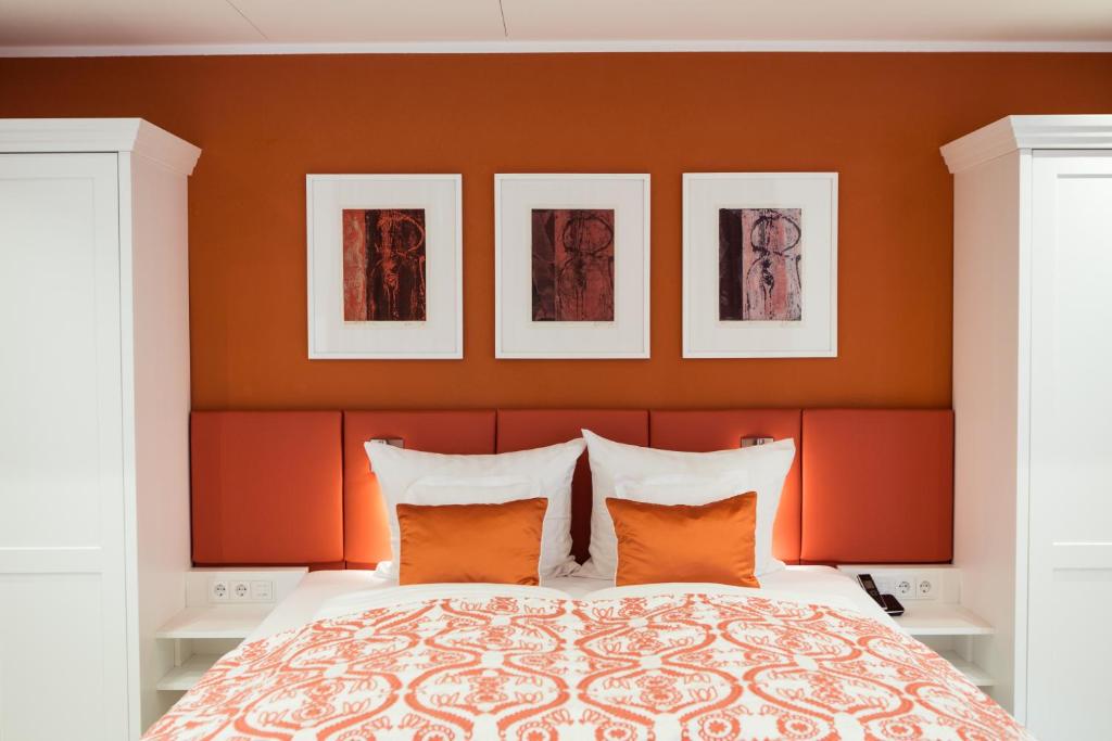 una camera da letto con pareti arancioni e un letto con cuscini arancioni di Passau - Suites a Passavia