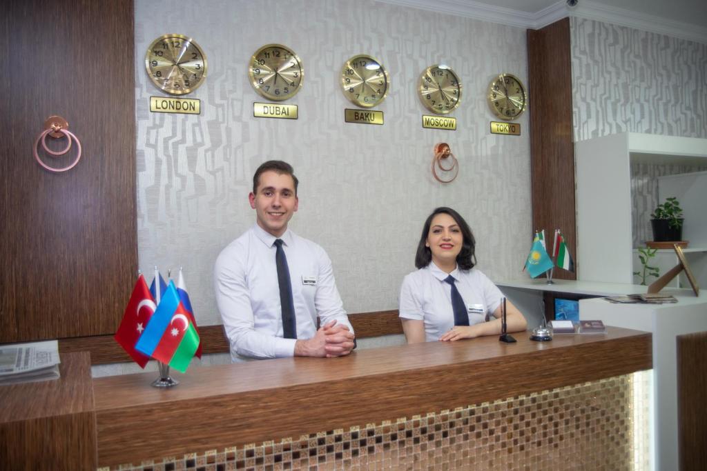 a man and a woman standing behind a desk with at Mildom Hotel Baku in Baku