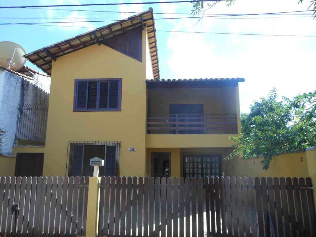 una casa amarilla con una valla delante de ella en Casa familiar en Arraial do Cabo