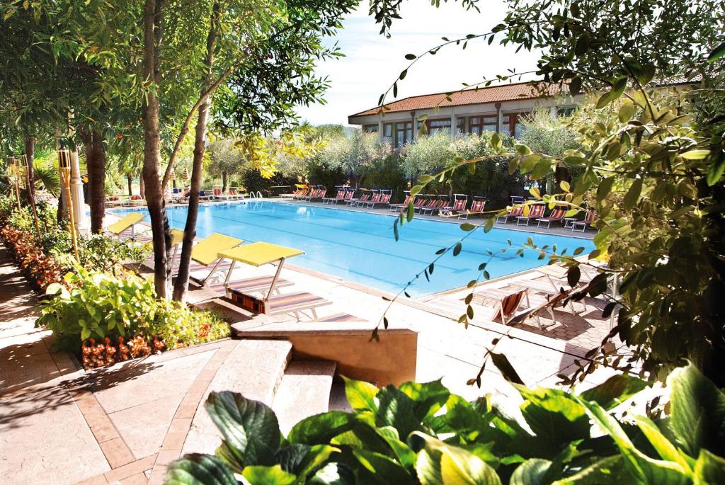 a large swimming pool with tables and chairs at Sporthotel Olimpo in Garda