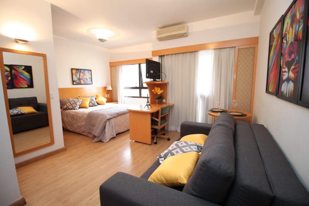 een woonkamer met een bank en een bed bij Flat 4 Estrelas Jardins in Sao Paulo